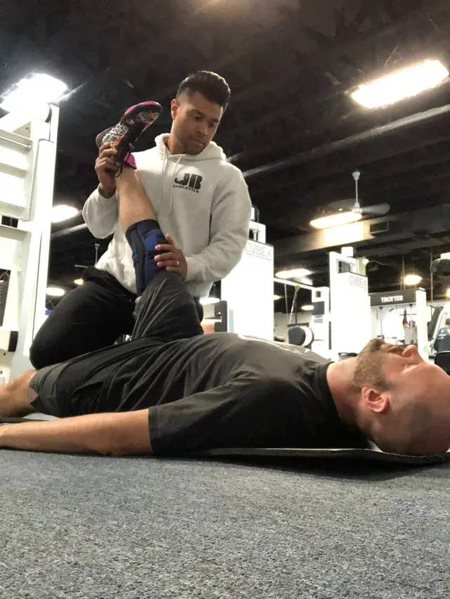 Jason Alfonso doing an assisted hamstring stretch with a client