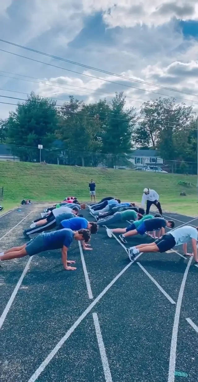 Young athletes doing push-ups on a running track during a team session
