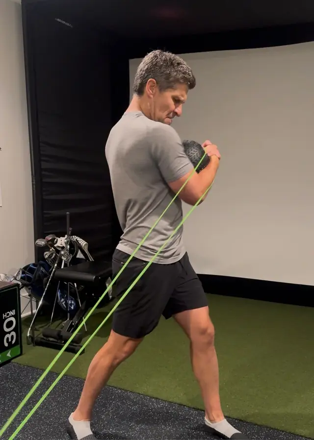 Golfer doing a cable rotation drill with a JB Athletics coach at home