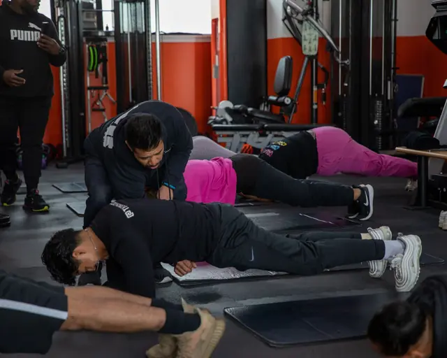 Jason Alfonso correcting a client's plank during a small group class
